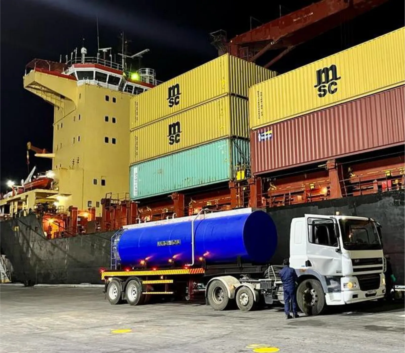 Collection tanker alongside a container ship at night